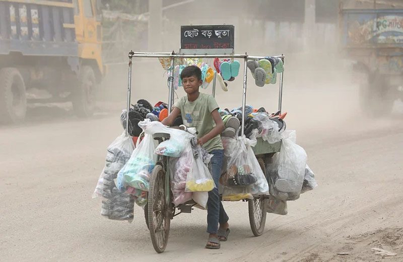 এই ধুলার সড়কে প্রতিদিন এভাবে ফেরি করে জুতা বিক্রি করে শিশুটি।